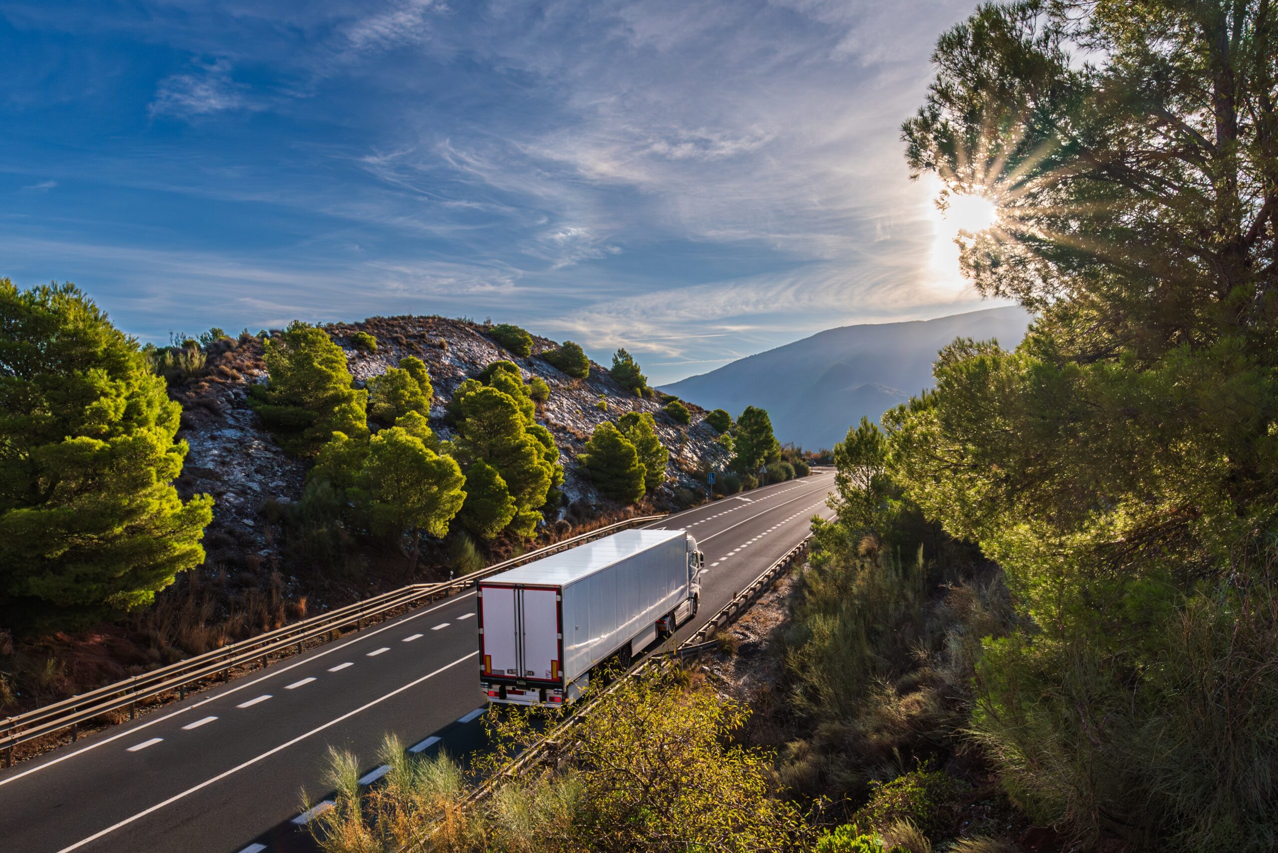 Refrigerated,Truck,Driving,Along,A,Mountain,Road,Surrounded,By,Forest